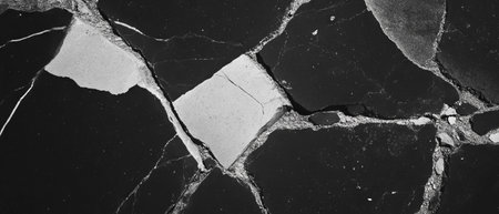 Cracked asphalt texture with irregular patterns in black and gray tonesの素材