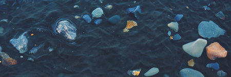 Black sand texture with fine ash and smooth stones by the waterの素材