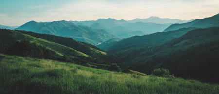 Serene mountain landscape featuring lush green hills and distant peaks under a clear skyの素材