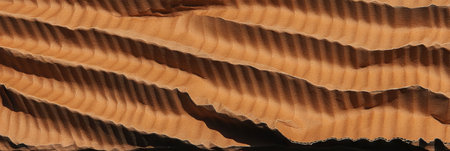 Dark beige corrugated cardboard texture showcasing rough edges and layered patternsの素材