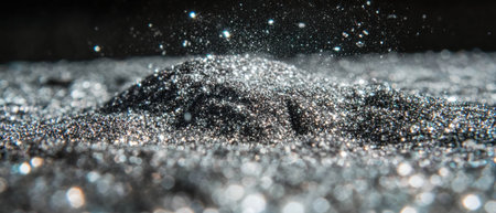 Sparkling silver glitter dust creating a shimmering overlay texture in dark backgroundの素材