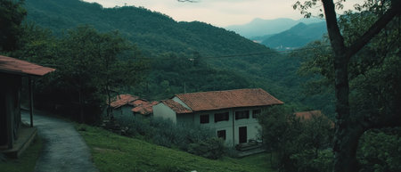 Peaceful village nestled in lush hills under an overcast skyの写真素材