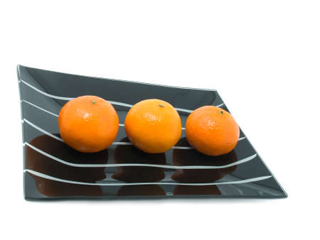  three mandarin on a plate  over white backgroundの写真素材