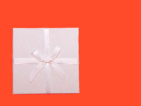 white gift box with ribbons on red background