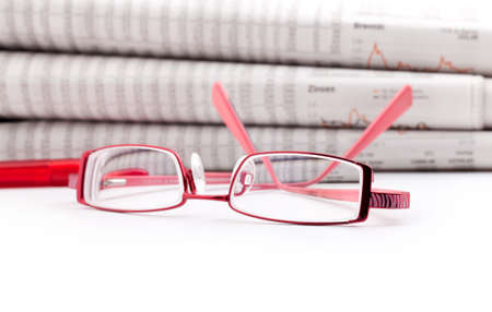 reading glasses lie before a big newspaper pileの写真素材