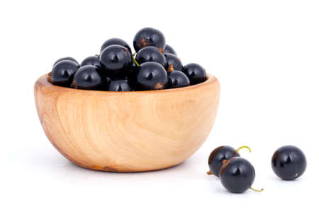 fresh black currants in a wooden bowl, over a white background.の写真素材