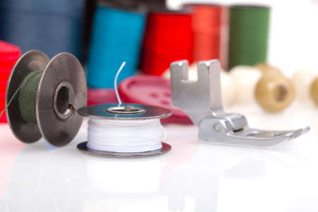 Metal spool of thread and coloured bobbins of threadの写真素材