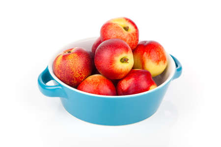 red ripe nectarine peaches on bowl,  isolated on whiteの写真素材
