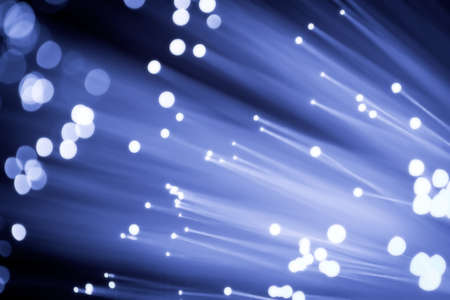 Close up on the ends of a selection of illuminated blue fiber optic light strands with black background.の写真素材