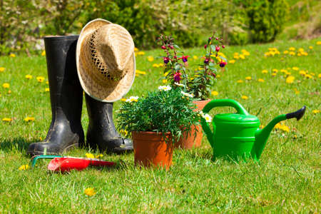 Gardening tools and a straw hat on the grass in the gardenの写真素材