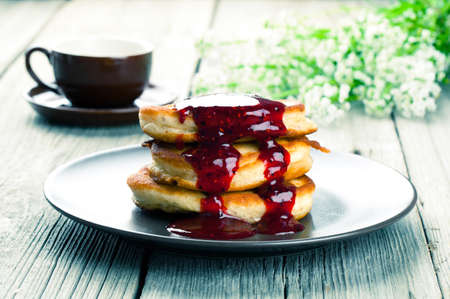 Delicious pancakes with raspberries sauce on the wooden kitchen tableの写真素材