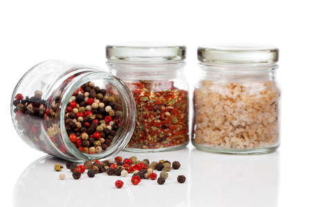 Glass jar with Colored Peppers Mix, red chili pepper and salt, on white background