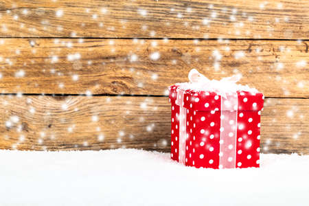 red gift for christmas on a wooden background with snowの写真素材