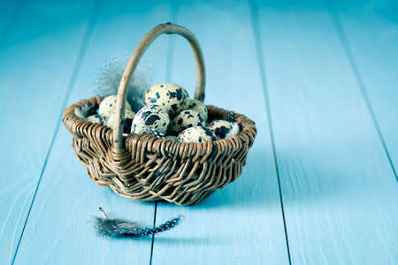 quail eggs in a wicker basket on blue wooden background