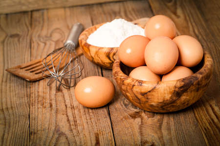 flour and eggs, ingredients for baking. on wooden backgroundの写真素材