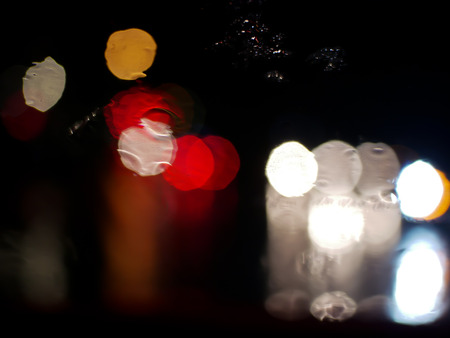 blurry traffic jam bokeh light view outside road from inside a car while raining , night cityscape...
