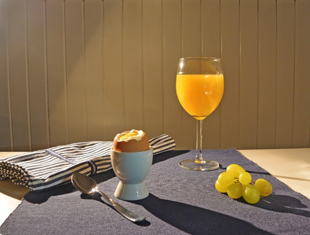 boiled eggs and orange juice for breakfast on a blue tableclothの写真素材