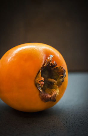 Diospyros kaki, also called persimmon, single fruit on dark background, selective focusの写真素材