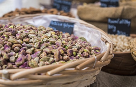 Background of basket of pistachios without shells, captured on street market, selective focus