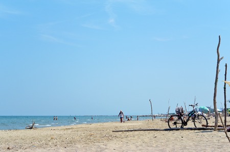 Summer camping with a tent and bicycle at a lonesome wild beach with a turquoise sea and blue sky in the background,の写真素材