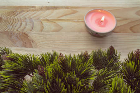 burning candle on wooden table decorated with fir tree branchesの写真素材