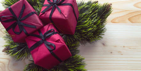 red gifts decorated with fir tree branches on wooden backgroundの写真素材