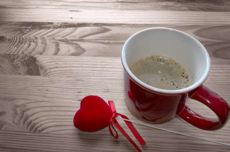 freshly made mug of coffee with red velvet heart on wooden backgroundの写真素材