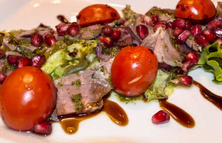 close up of meat salad with vegetables and pomegranate seedsの写真素材