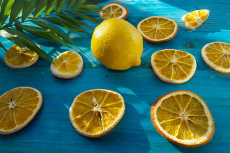 orange slices and lemon on blue wooden background with palm leaf partの写真素材