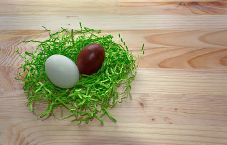 chocolate and white egg in green nest on wooden backgroundの写真素材