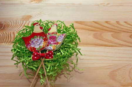 couple of hens painted with flowers lying in nest on wooden backgroundの写真素材