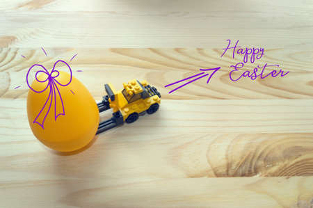 concept of Easter preparation with toy loader and big yellow eggの写真素材