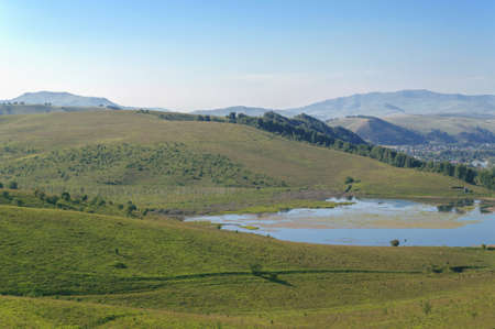 Altai at summer with lake view and village surrounded by green hills
