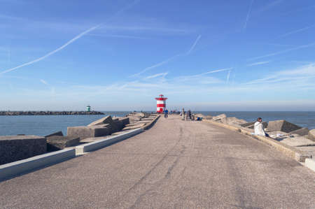 Hague, The Netherlands, October 05, 2018: People relaxing on the pier with lighthouse on sunny dayのeditorial素材