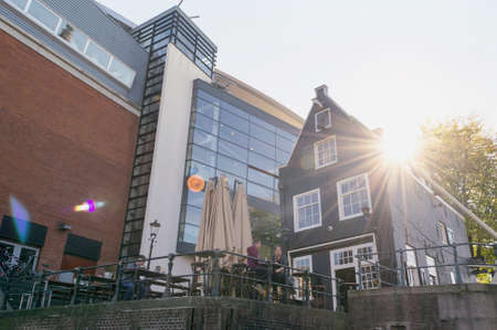 Amsterdam, The Netherlands, October 10, 2018: view from below on people at cafes table and warm sun rays shining through the roofのeditorial素材
