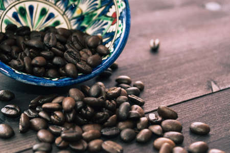 Roasted coffee beans in oriental bowl on dark woodenの写真素材