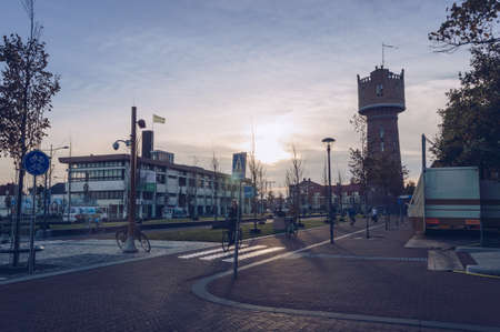 Den Helder, The Netherlands, October 13, 2018: view of citizen of Den Helder riding bicycles in the evening with Water towerのeditorial素材