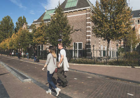 Amsterdam, The Netherlands, October 11, 2018: couple walking near Rijks museum walls on sunny dayのeditorial素材