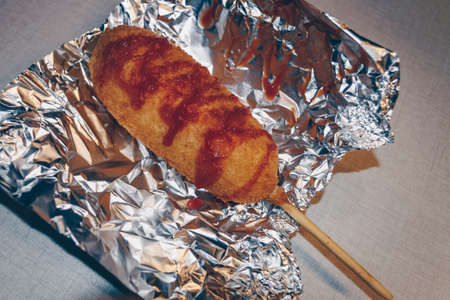 freshly made hot corn dog inside of foil to preserve heat