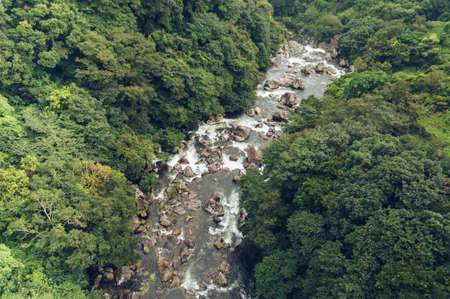 view from above on fast mountain river flow and abundant forest surrounding itの写真素材