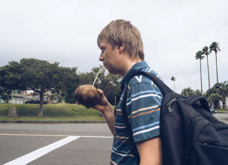 man is drinking freshly opened coconut juice at tropical islandの写真素材