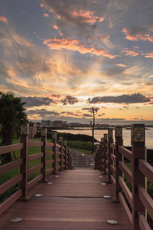 oriental wooden bridge decorated with lanterns at Hamdeok Beach with scenic susnet on backgroundの写真素材
