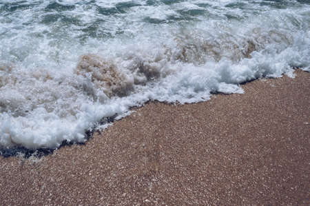 sea foam and sand on hot sunny windy day