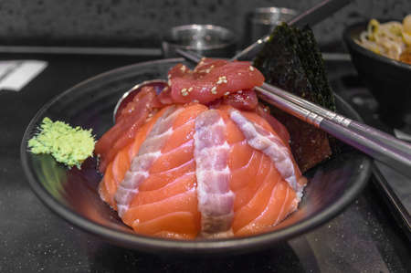 freshly made rice covered with sliced tuna and salmon pieces with wasabi and nori