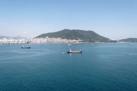 view from above on cityscape of Busan and vast sea with sailing shipsの写真素材
