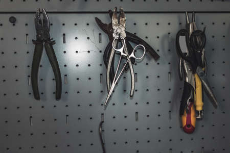 view of iron board with hooks and hanging on them tools : wire cutters, pliers, scissors and screwdriverの写真素材