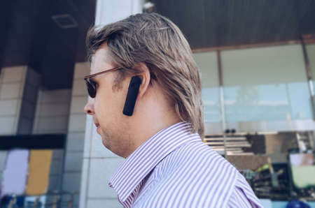 walking  in the city blond man in sunglasses with handsfree headset