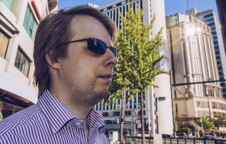man in sunglasses walking in the modern city on sunny day