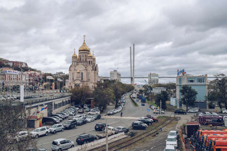 Vladivostok, Russia - October 05, 2020: view from above on parked cars, railway track, bridge and orthodox church as part of cityscape on gloomy dayのeditorial素材