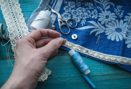 woman holding needle for basting fabric oing to prick lace to the linen clothesの写真素材